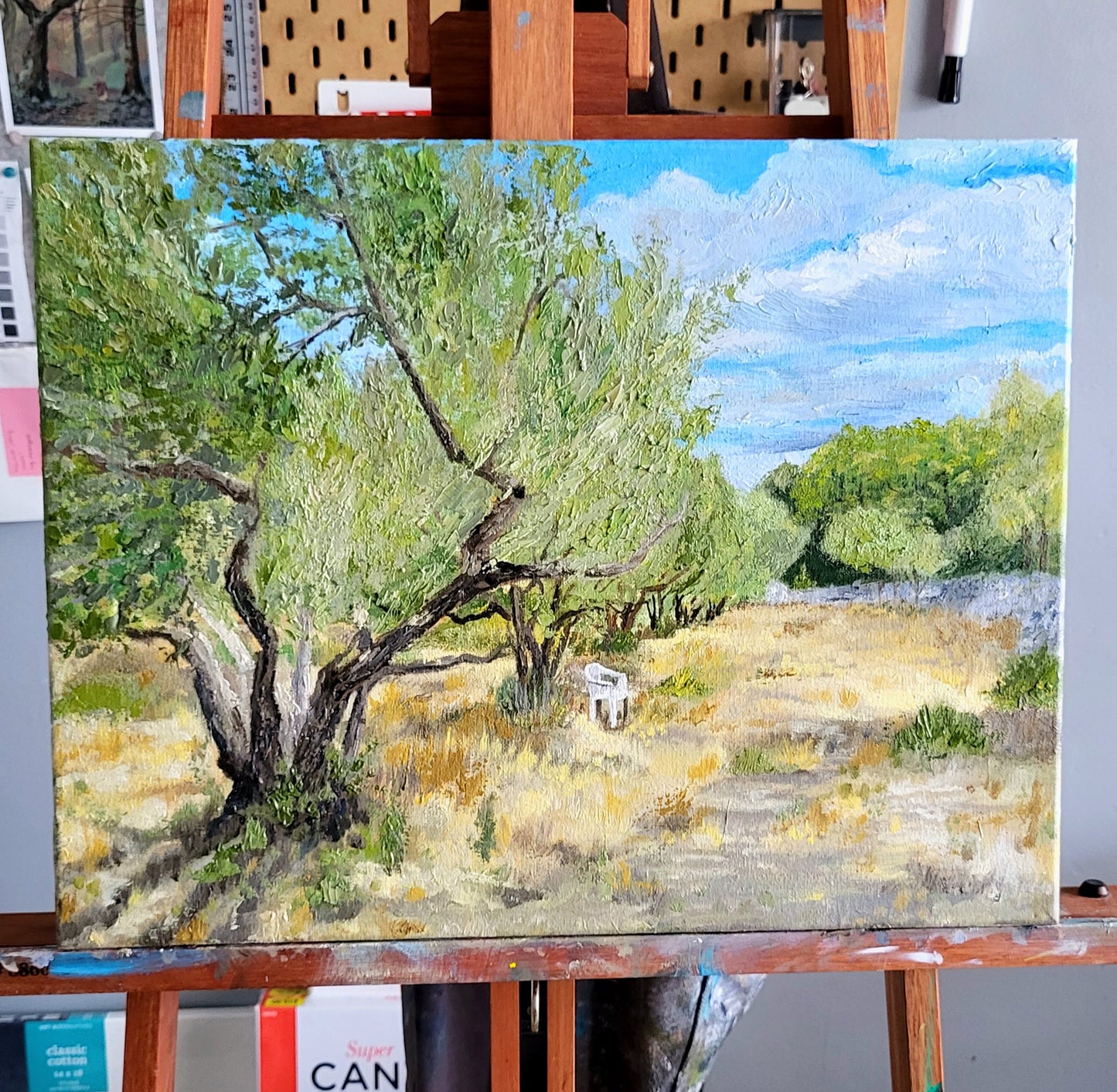 Original oil painting on canvas by Jessie Bettersworth. Thick oil paint texture of an olive grove with a single white chair.